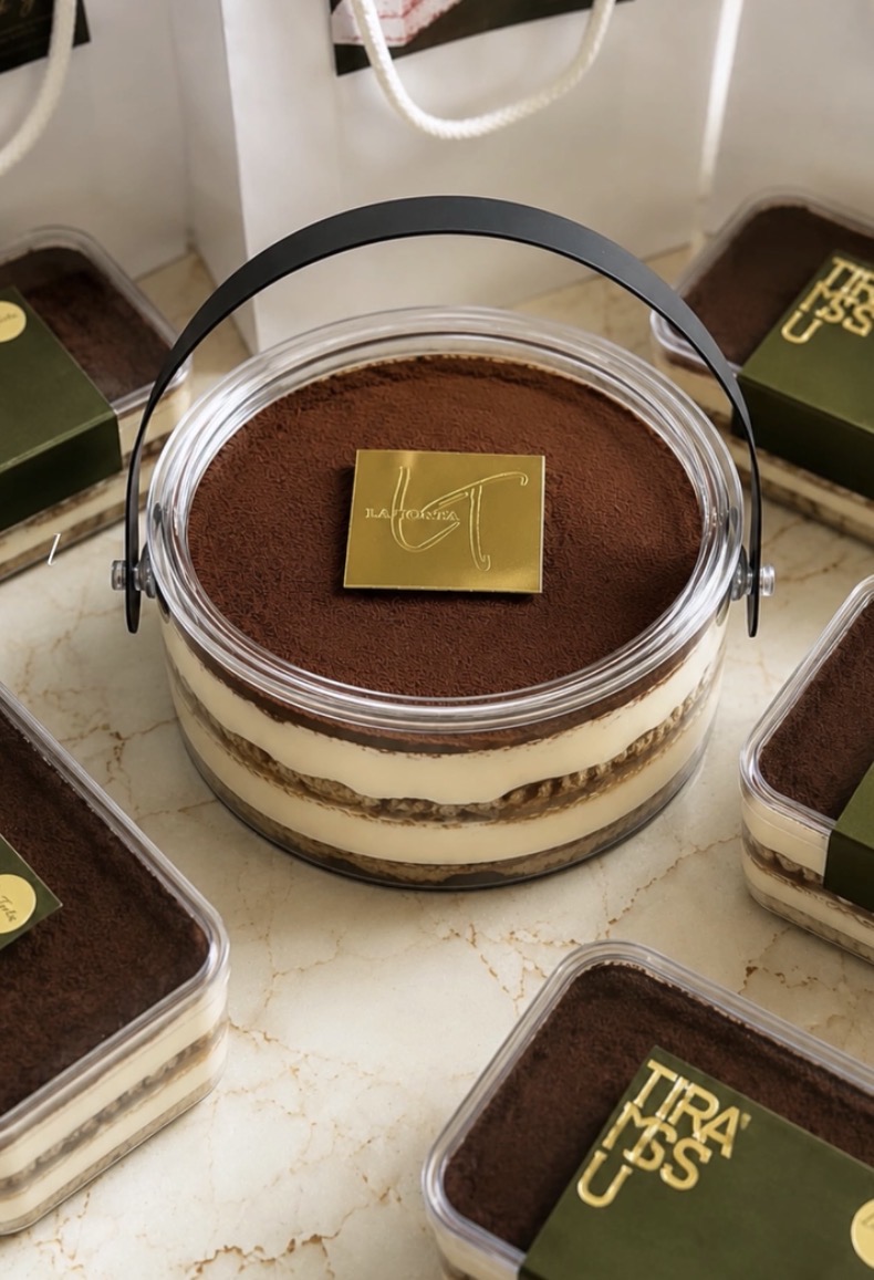Signature tiramisu tub with gold La Torta plaque and cocoa dusting